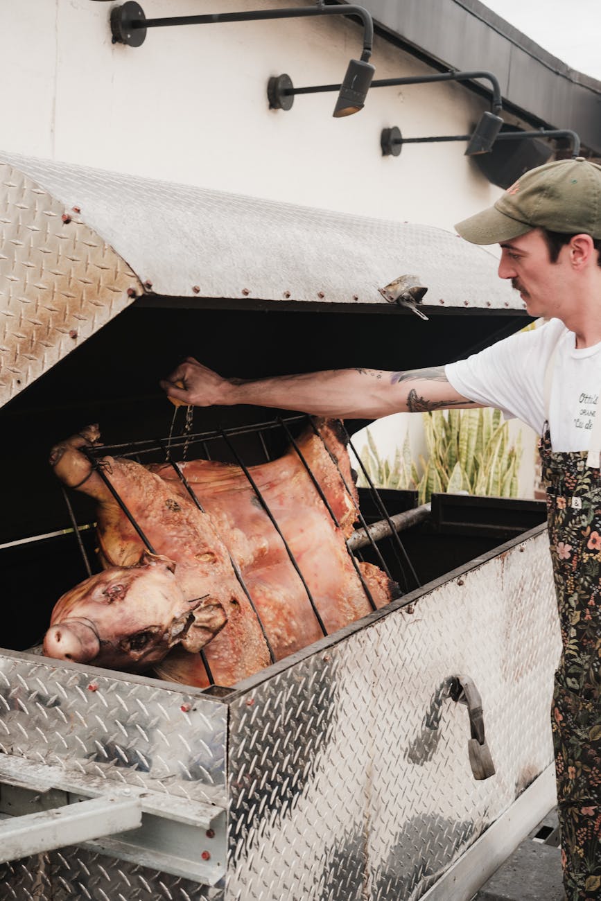 man roasting pork meat on barbecue learning barbecuing methods in UK with smoker